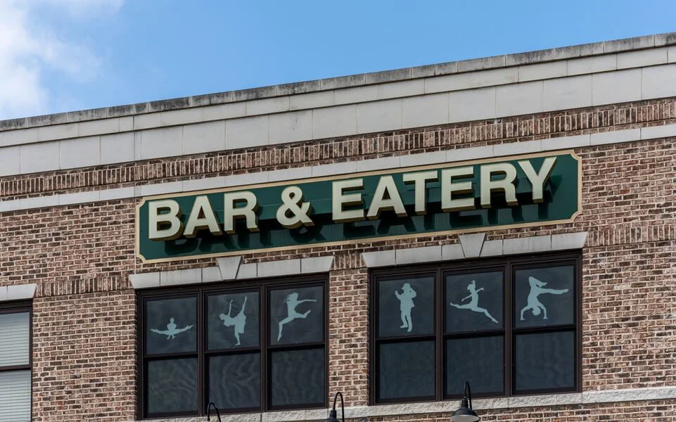 A bar and eatery sign on brick building.